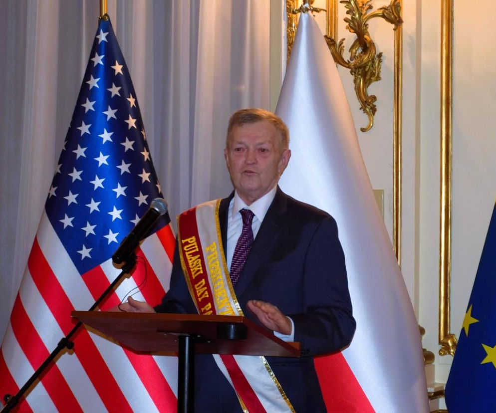 Richard Zawisny za pulpitem między flagami USA i Polski. O Paradzie Pułaskiego w Nowym Jorku przeczytasz na SE USA.