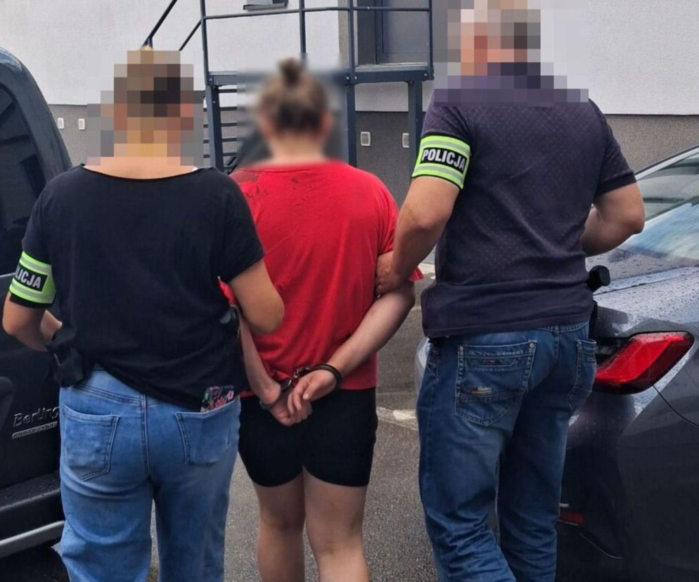 Zatrzymana kobieta w kajdankach prowadzona przez dwoje policjantów. O wypadku w Hucie Dąbrowie przeczytasz w Radioplus.