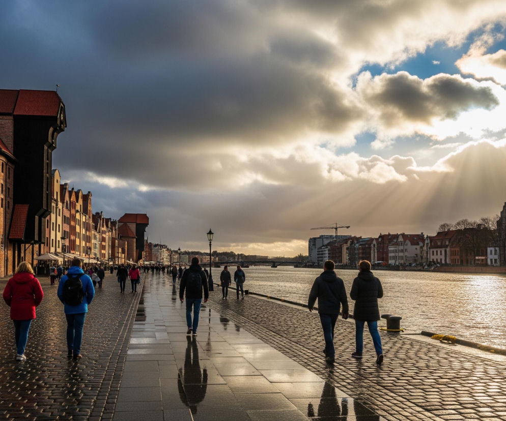 Po lewej stronie kadru dominuje rząd kolorowych, ceglanych kamienic, z których wyróżnia się duży, ciemny budynek z charakterystycznym, czerwonym dachem i drewnianą konstrukcją dźwigu. Przed kamienicami rozciąga się szeroki, wybrukowany deptak z granitową ścieżką pośrodku, na którym spaceruje wiele osób w zimowych ubraniach, tworząc dynamiczną scenę. Po prawej stronie biegnie rzeka, której powierzchnia odbija światło słoneczne, tworząc jasne refleksy, a na dalszym planie widoczne są kolejne budynki i most. Niebo pokrywają ciężkie, ciemne chmury, które w prawej części obrazu rozstępują się, ukazując błękitne niebo i promienie słońca przebijające się przez obłoki.