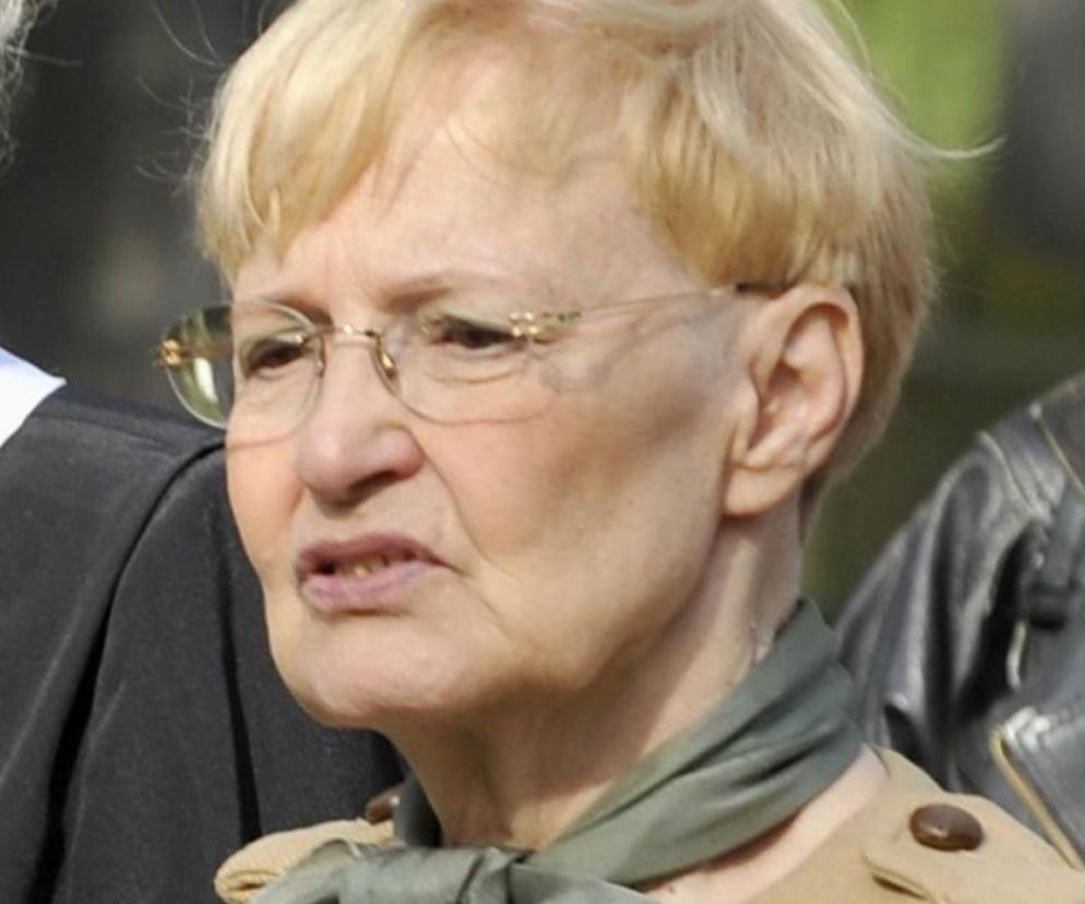 Edyta Wojtczak, legenda polskiej telewizji, z krótkimi blond włosami i okularami, w jasnym ubraniu i zielonej apaszce, opowiada o trudnym czasie spędzanym w domu z powodu upałów. Więcej o wyzwaniach starszych osób przeczytasz na naszym portalu.