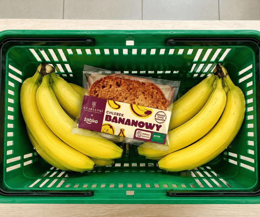 Chlebek bananowy i kiście bananów w zielonym koszyku. O walce Żabki z marnowaniem żywności przeczytasz na SE Superbiz.