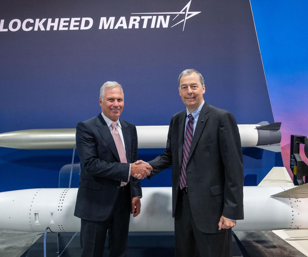 Dwaj uśmiechnięci mężczyźni w garniturach podają sobie ręce na tle modeli pocisków i logo Lockheed Martin. O współpracy z Avio przeczytasz na SE Portal Obronny.