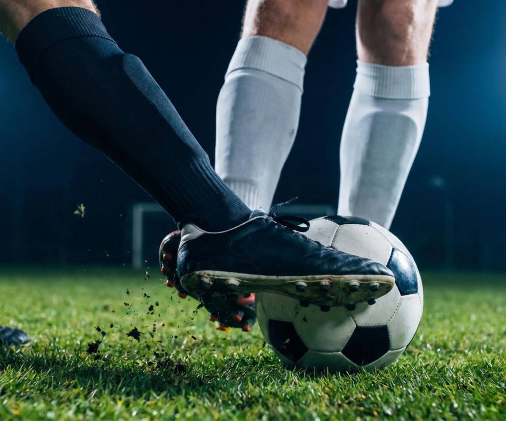 Dwóch piłkarzy w akcji na boisku, jeden w czarnym stroju, drugi w białym, walczą o piłkę, lecąca ziemia z butów. Sportowe emocje towarzyszące MŚ 2026 i meczowi Maroka z Holandią znajdziesz na naszym portalu.