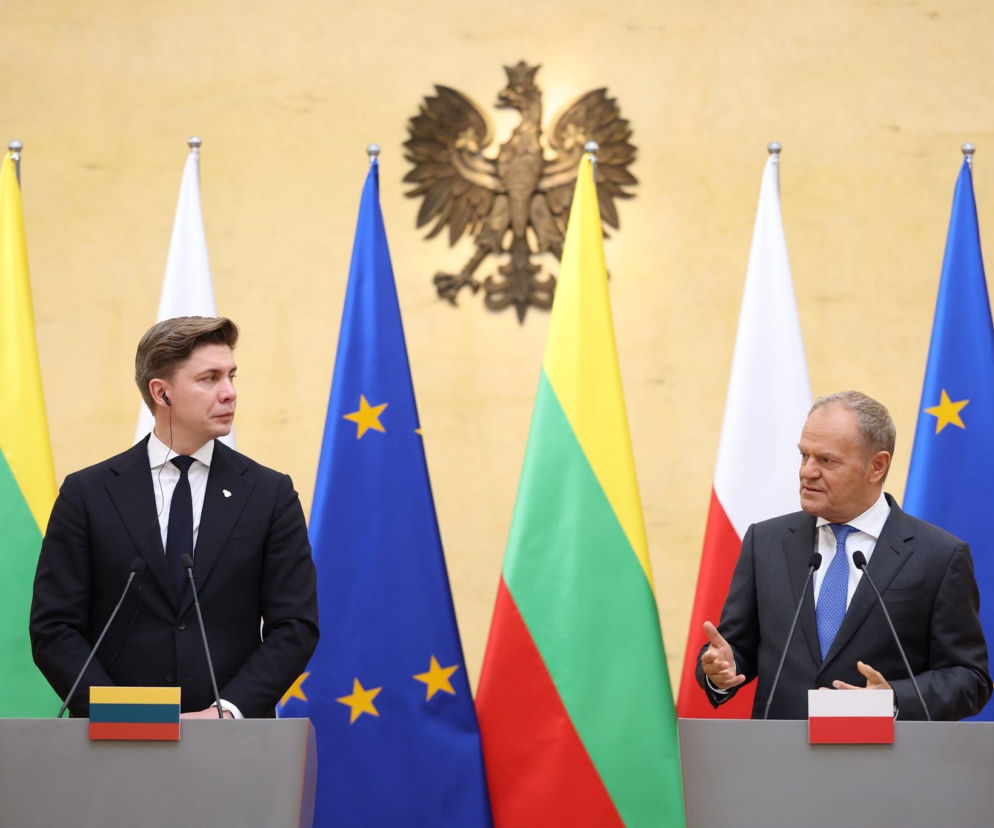 Premierzy Donald Tusk i Mindaugas Sinkevičius przy mównicach na tle flag. O relacjach informuje SE Portal Obronny.