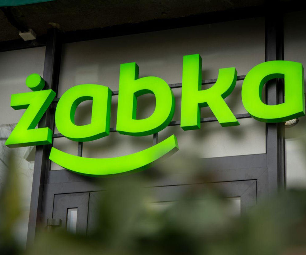 Zielony, podświetlony logotyp sieci Żabka nad wejściem do sklepu. O rekordowych wynikach Grupy Żabka przeczytasz w Eska.