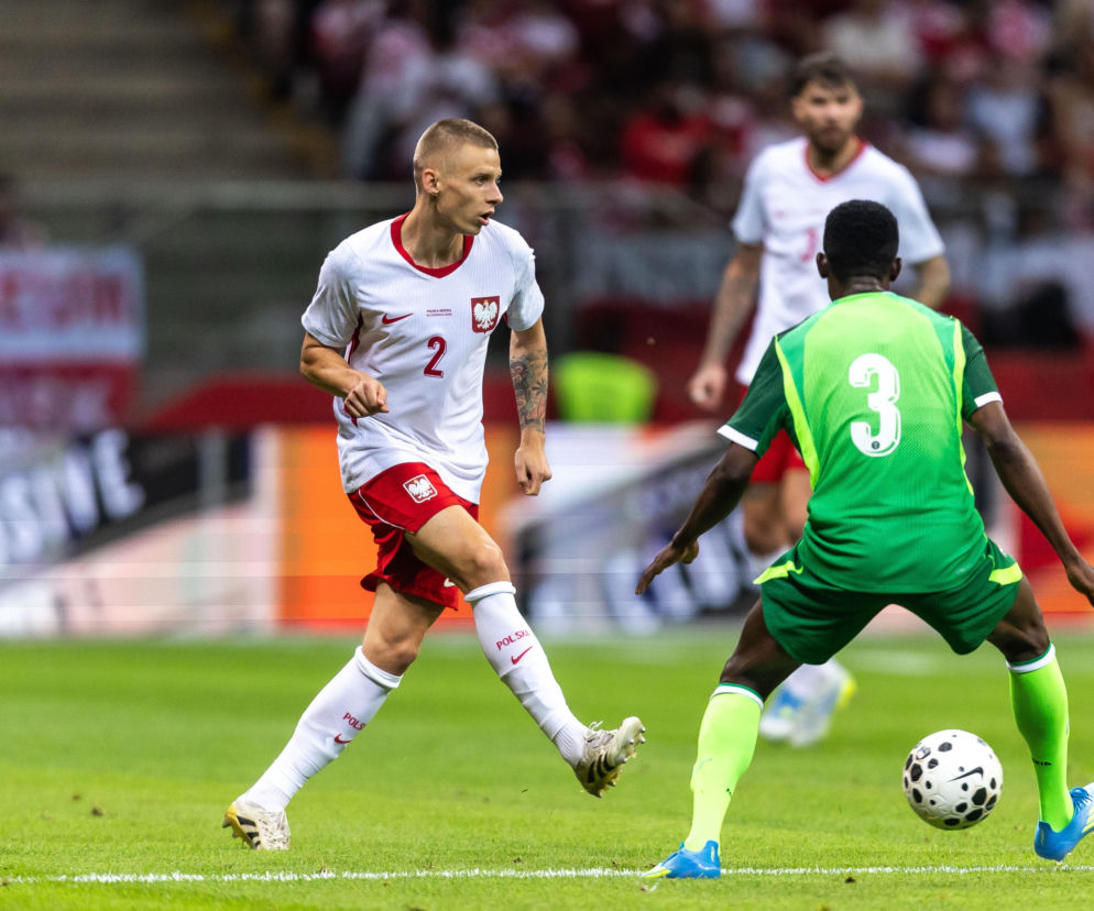 Norbert Wojtuszek w białym stroju kadry walczy o piłkę z rywalem. O powołaniu piłkarza przeczytasz na SE Supersport.