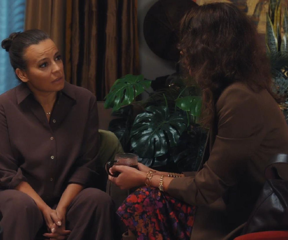 Paulina Lipska i Magda Budzyńska rozmawiają na kanapie w mieszkaniu Budzyńskich. Paulina (po lewej), ubrana na brązowo, patrzy z powagą na Magdę (po prawej), która trzyma kubek. Opowieść Pauliny o mężu wzbudza współczucie Magdy, o czym przeczytasz na Super Seriale.