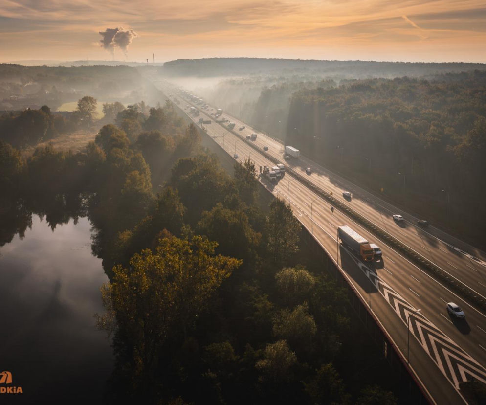 Autostrada A4 z lotu ptaka o wschodzie słońca. Trasa biegnie przez las, obok jeziora. O A4 przeczytasz na Architektura.