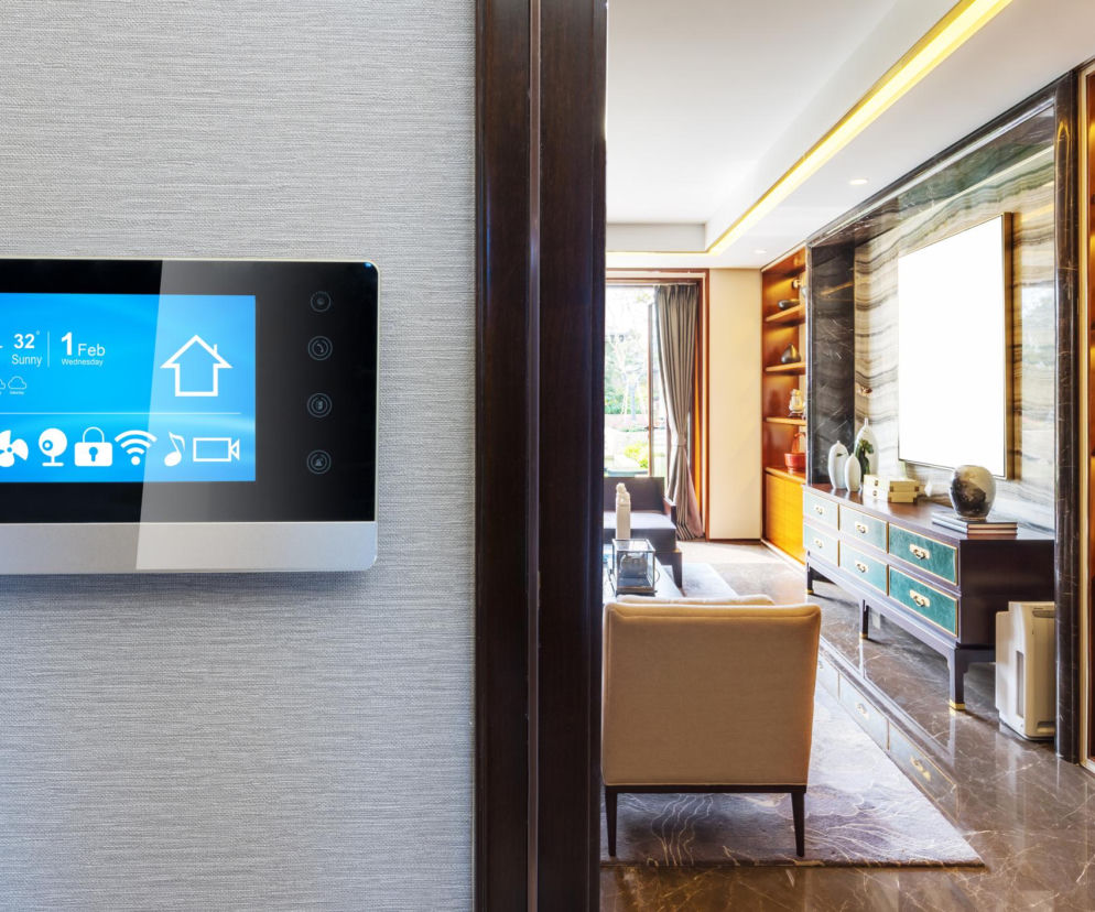Panel sterowania smart home na ścianie obok salonu. O technologii wspierającej domowników przeczytasz na Urządzamy.