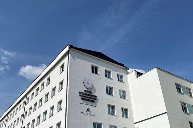 Budynek Szpitala Specjalistycznego im. Jędrzeja Śniadeckiego w Nowym Sączu, z logiem Małopolski, na tle błękitnego nieba z delikatnymi chmurami. O dużych zmianach i inwestycjach w sądeckiej onkologii, a także o nowym sprzęcie, przeczytasz na naszym portalu.