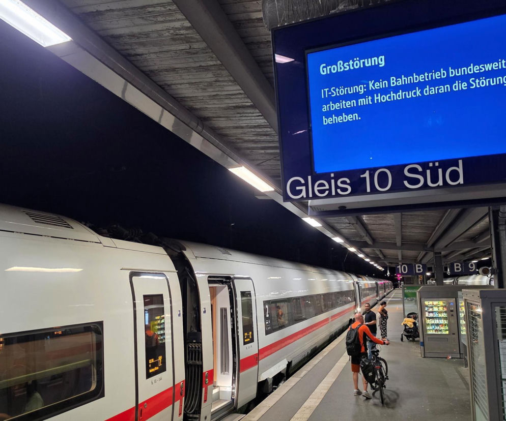Pociąg Deutsche Bahn stoi na peronie Gleis 10 Süd w Niemczech, a na tablicy informacyjnej widnieje komunikat o awarii systemu IT, która wstrzymała ruch kolejowy w całym kraju. Więcej o paraliżu transportowym przeczytasz na naszym portalu.
