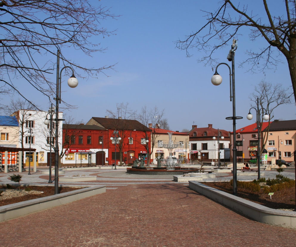 Rynek w Koziegłowach z fontanną i kolorowymi kamienicami. O historii tego śląskiego miasta przeczytasz na Eska Śląskie.