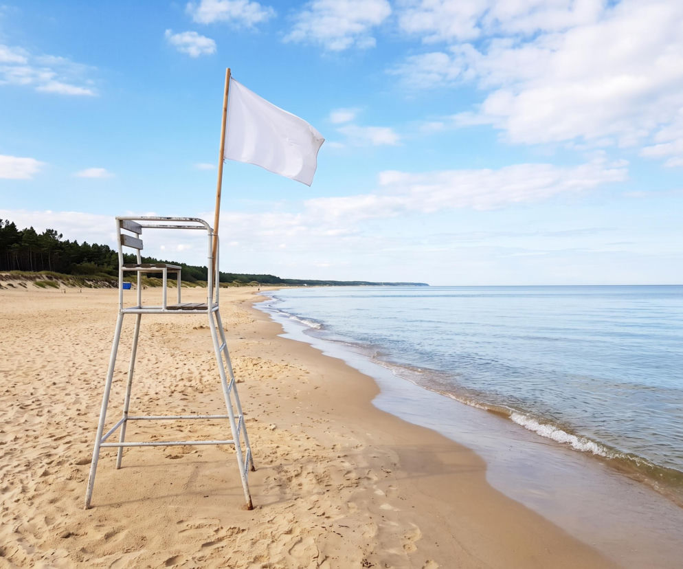 Biała flaga na wieży ratowniczej na pustej plaży w Grzybowie. O warunkach nad morzem przeczytasz na SE Szczecin.