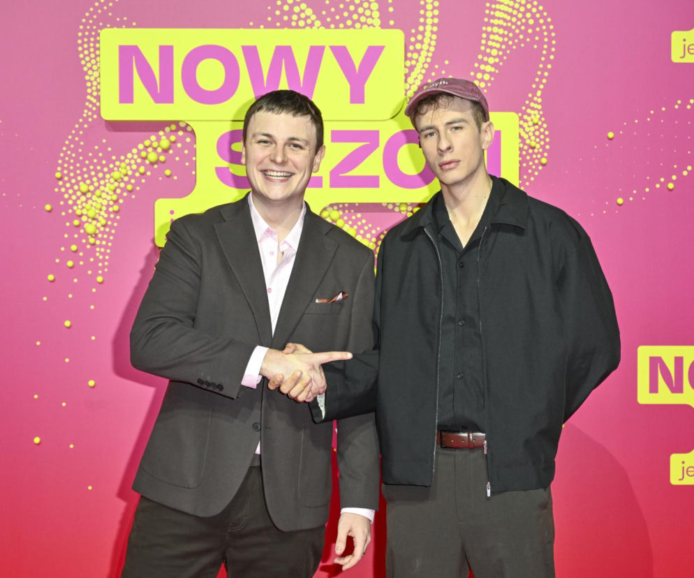 Adam Zimmermann i Jakub Stulin podają sobie ręce na tle ścianki TVN. O ich udziale w Azja Express przeczytasz w Eska.
