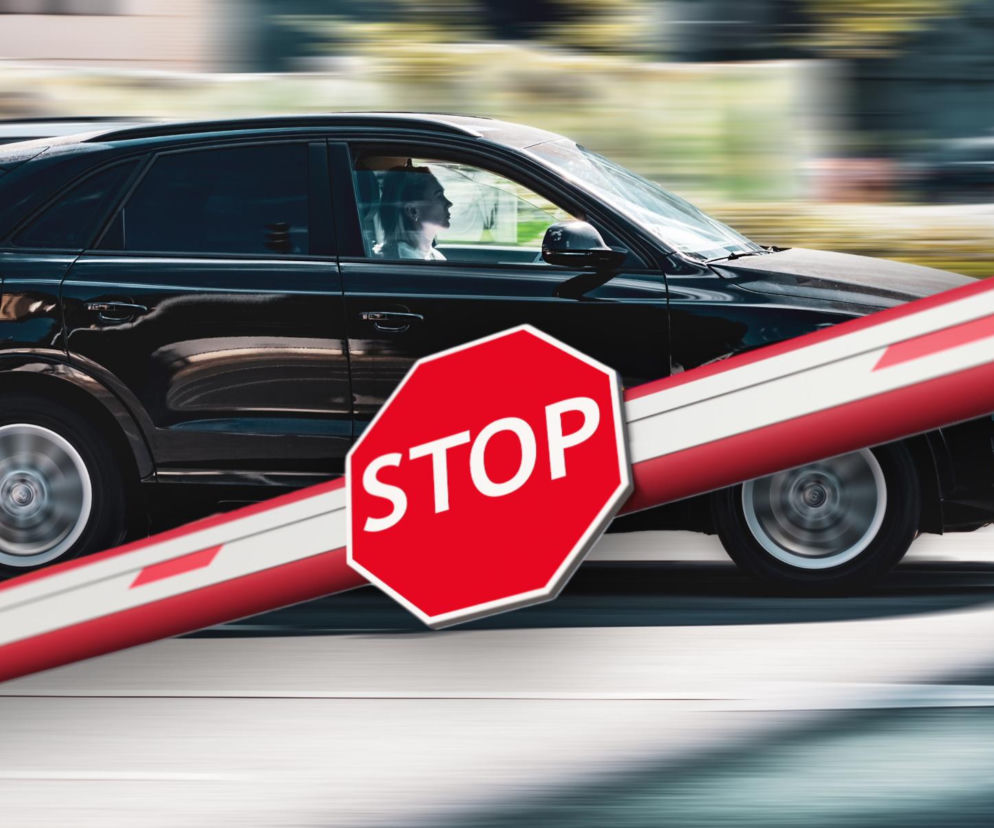 Czarne auto typu SUV za szlabanem ze znakiem STOP. O zakazie wjazdu dużych aut do miast przeczytasz na SE.