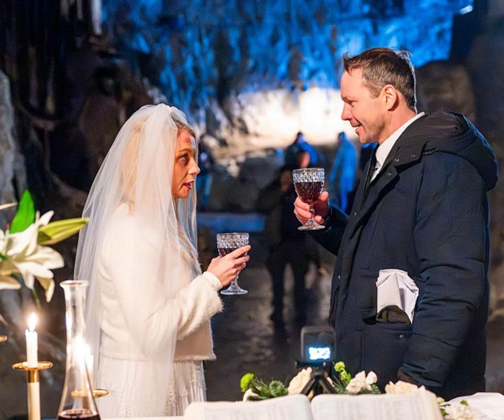 Emilka (Anna Ilczuk) w ślubnej stylizacji i Mateusz (Lesław Żurek) z kieliszkami wina w dłoniach, patrzą na siebie z niepokojem. Scena z serialu Pierwsza miłość odcinek 4150, gdzie Emilka jest w śmiertelnym niebezpieczeństwie. Więcej o dramatycznych losach bohaterów na portalu Super Seriale.