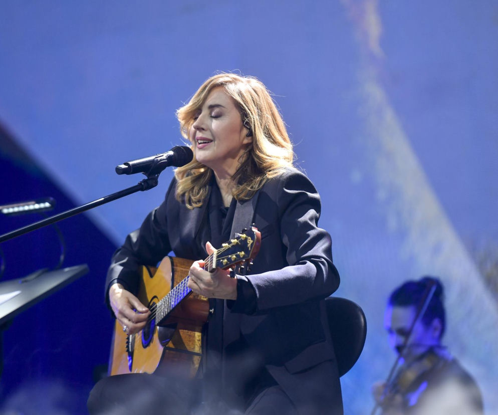 Edyta Bartosiewicz gra na gitarze i śpiewa do mikrofonu na scenie. O nowej trenerce show przeczytasz w serwisie Eska.