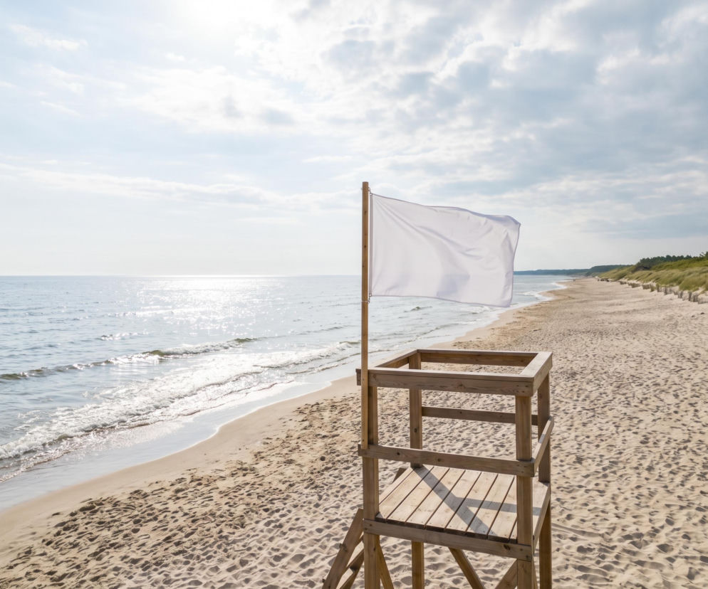 Biała flaga na wieży ratowniczej na pustej plaży. O bezpiecznych kąpielach w Chłopach przeczytasz na SE Szczecin.