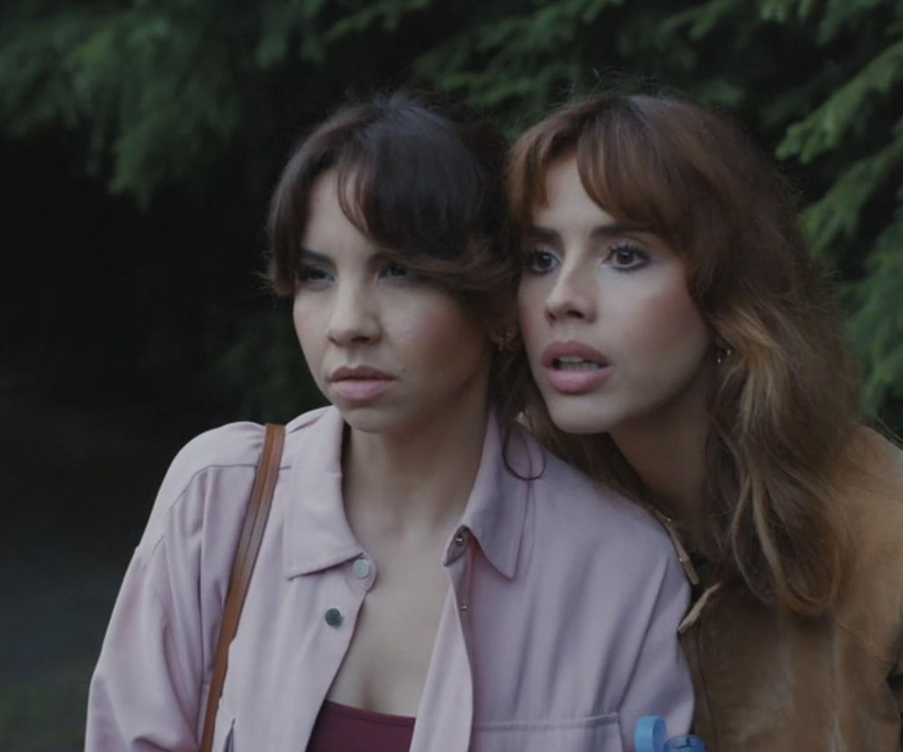 Aneta i Kama z M jak miłość zaniepokojone, wyglądają na przestraszone. Aneta w różowej koszuli i Kama w brązowej kurtce, obie z rozpuszczonymi włosami, intensywnie obserwują coś poza kadrem. Więcej o ich perypetiach znajdziesz na Super Seriale.