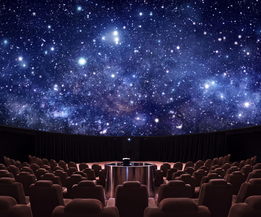 Wnętrze planetarium z rzędami foteli pod kopułą z gwieździstym niebem. O inwestycji Cavatiny przeczytasz na Muratorplus.