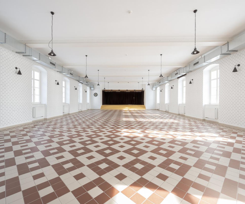 Jasna sala bankietowa w klasztorze w Lubomierzu z wzorzystą posadzką. O renowacji wnętrz przeczytasz w serwisie Architektura.