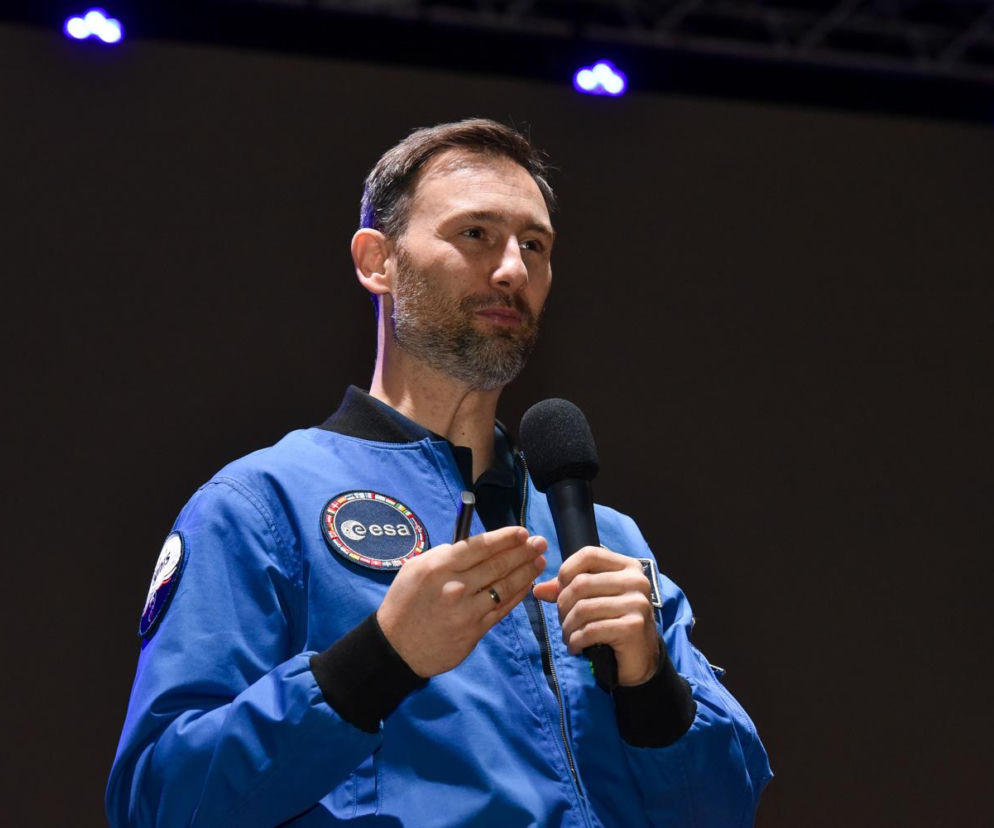 Astronauta Sławosz Uznański w niebieskim kombinezonie ESA przemawia do mikrofonu. O Kongresie Zdrowe Miasta przeczytasz w SE.