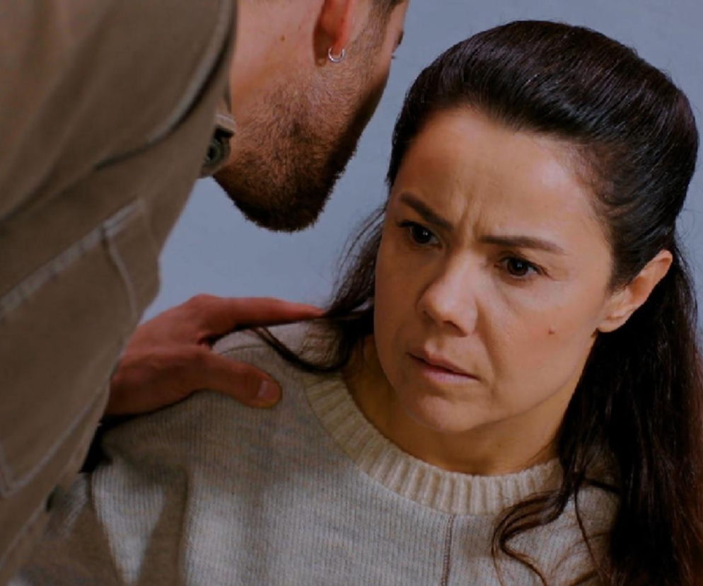 Cihan pochylony nad zszokowaną Gonul, która słucha szokujących wiadomości o swojej córce. Jego dłoń spoczywa na jej ramieniu. Scena z serialu Miłość i nadzieja odzwierciedla dramatyczne wydarzenia, które można przeczytać na portalu Super Seriale.