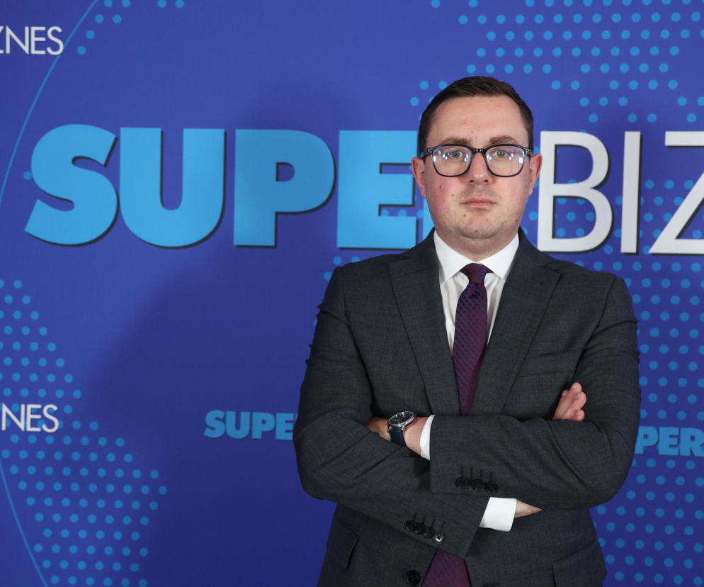 Minister energii Miłosz Motyka na tle logotypu Super Biznes. O odbudowie przemysłu przeczytasz na SE Superbiz.