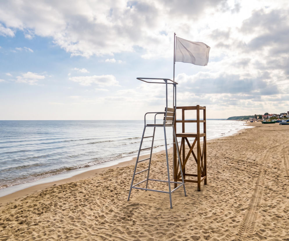 Wieża ratownicza z białą flagą na pustej plaży w Chłopach. O bezpiecznych kąpielach przeczytasz na SE Szczecin.