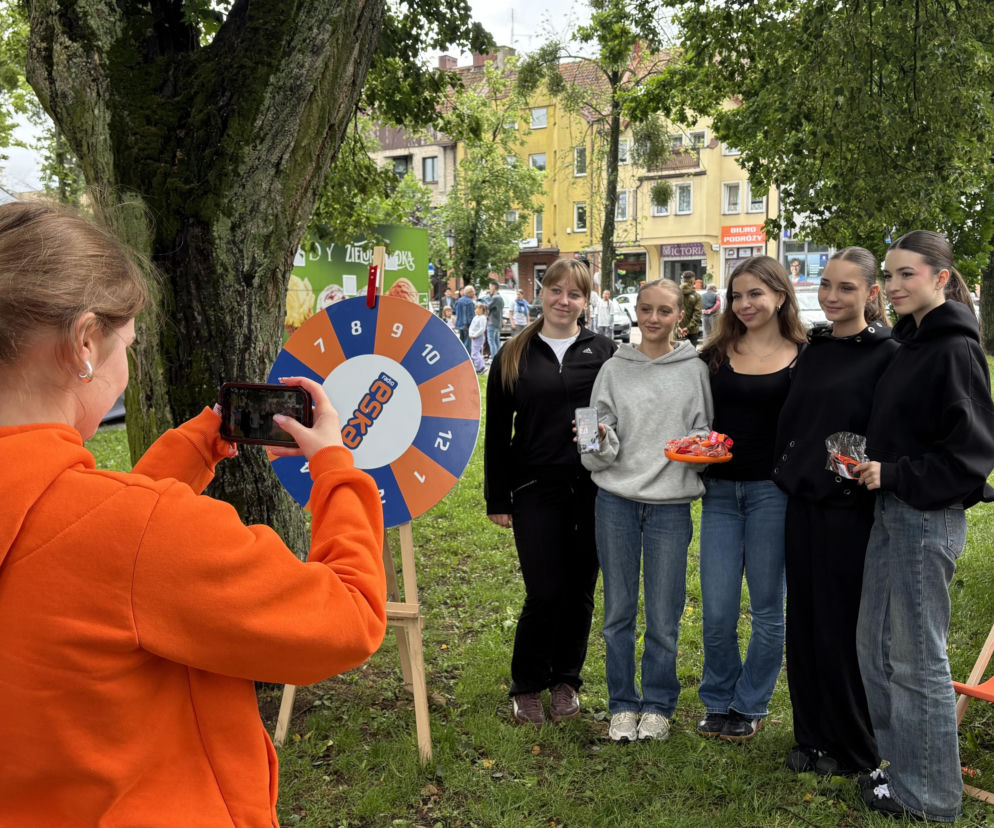 Dziewczyna fotografuje telefonem grupę nastolatek przy kole fortuny Radia Eska. O festiwalu pisze Eska Olsztyn.