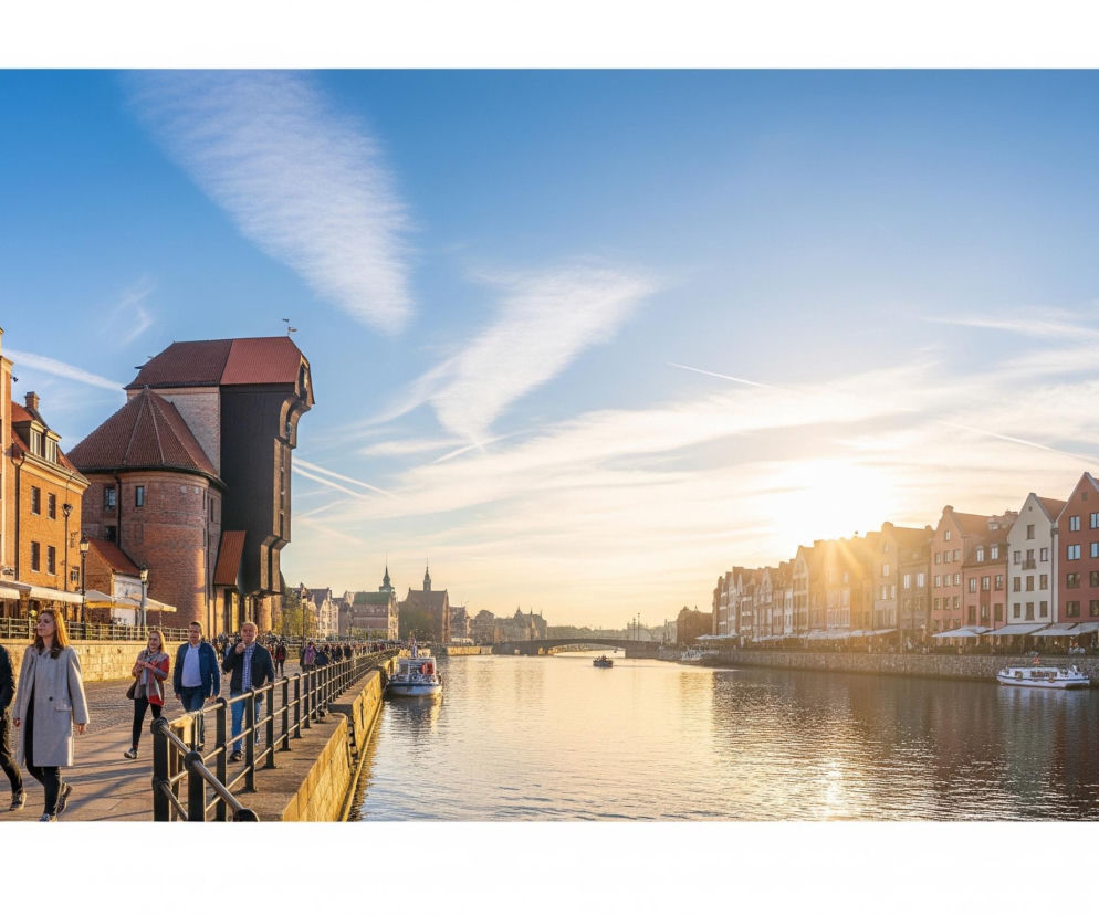 Gdańsk o wschodzie słońca, panorama nabrzeża z historycznym Żurawiem i kolorowymi kamienicami, nad rzeką Motławą, w tle błękitne niebo z promieniami słońca. Turyści spacerują po bulwarze. Więcej o turystyce w Polsce na Super Biznes.