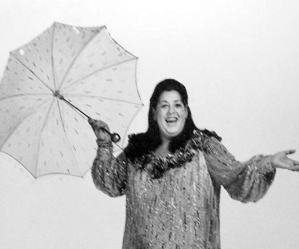 Uśmiechnięta wokalistka Cass Elliot trzyma jasny parasol. O mitach dotyczących jej śmierci przeczytasz na EskaRock.