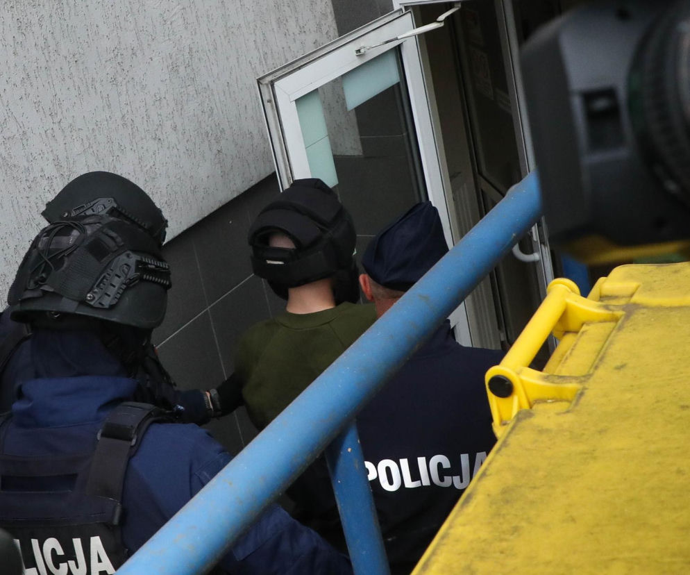 Uzbrojeni policjanci wprowadzają zatrzymanego do budynku. O działaniach służb w szkołach przeczytasz w serwisie Eska.
