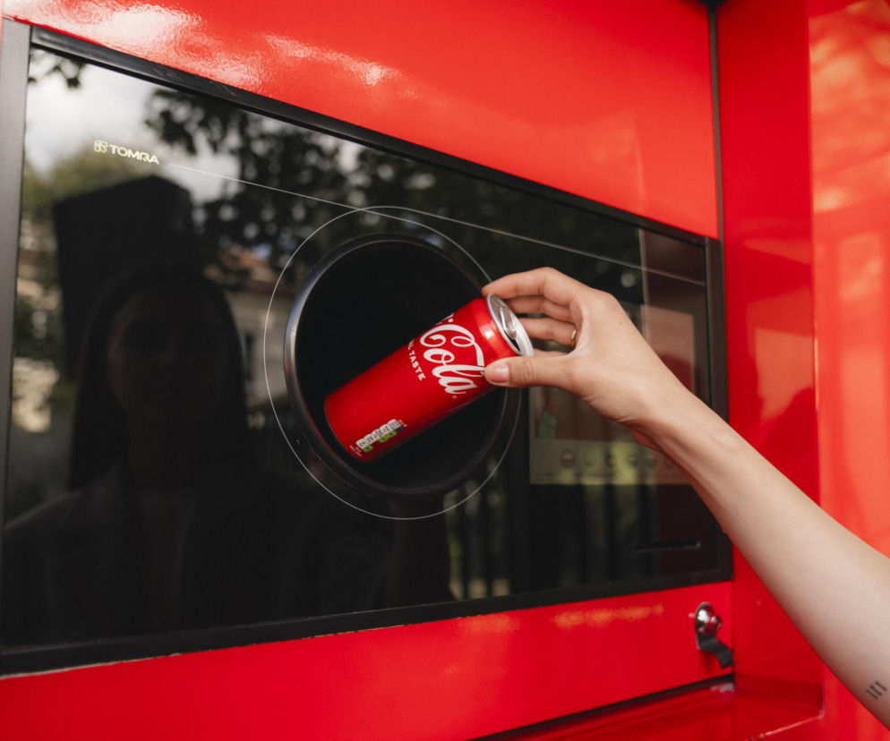 Ręka osoby wkładającej puszkę Coca-Cola do automatu kaucyjnego. O recyklingu i raporcie ESG przeczytasz na SE.