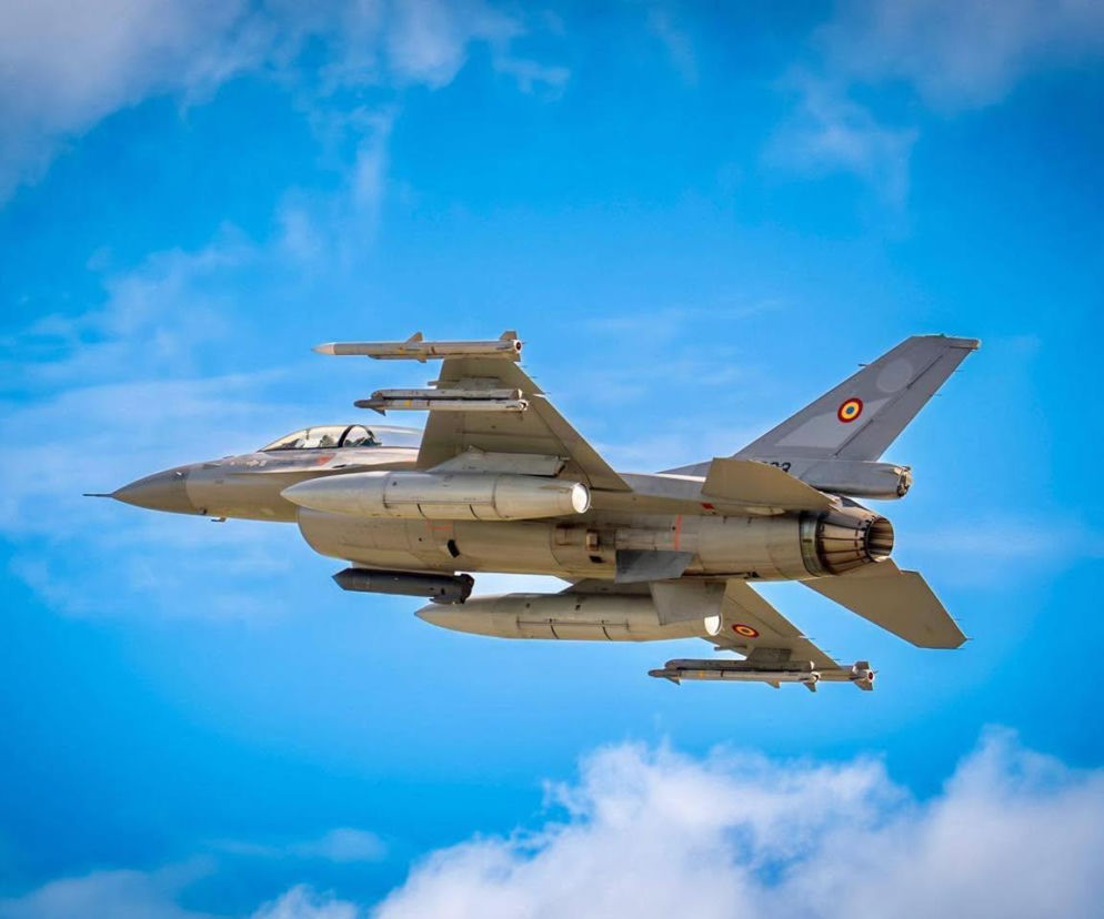 Rumuński myśliwiec F-16 leci na tle niebieskiego nieba z chmurami. O incydentach powietrznych czytaj na SE Portal Obronny.