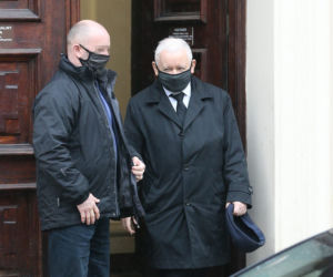 Pięciu ochroniarzy prowadzi Kaczyńskiego do bramy