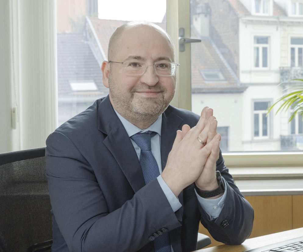 Europoseł Adam Bielan ze złączonymi dłońmi uśmiecha się do zdjęcia. O sprawie wyjazdu Zbigniewa Ziobry przeczytasz na SE Polityka.