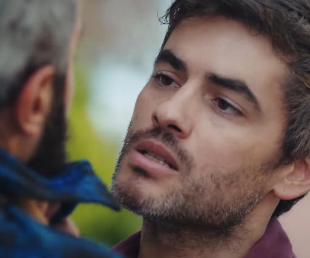 Mężczyzna o ciemnych włosach i z zarostem, intensywnie wpatrujący się w postać znajdującą się poza kadrem, w emocjonalnym ujęciu z serialu Dziedzictwo, gdzie Poyraz odkrywa sekret Nany i Yusufa. Więcej o dramatycznych wydarzeniach i zwrotach akcji w 879. odcinku na Super Seriale.