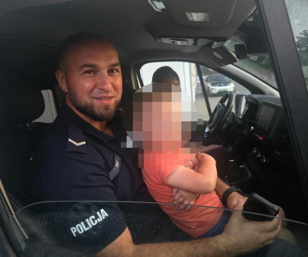 Uśmiechnięty policjant w radiowozie trzyma na kolanach małe dziecko. O zdarzeniu w Garwolinie przeczytasz na Eska Siedlce.
