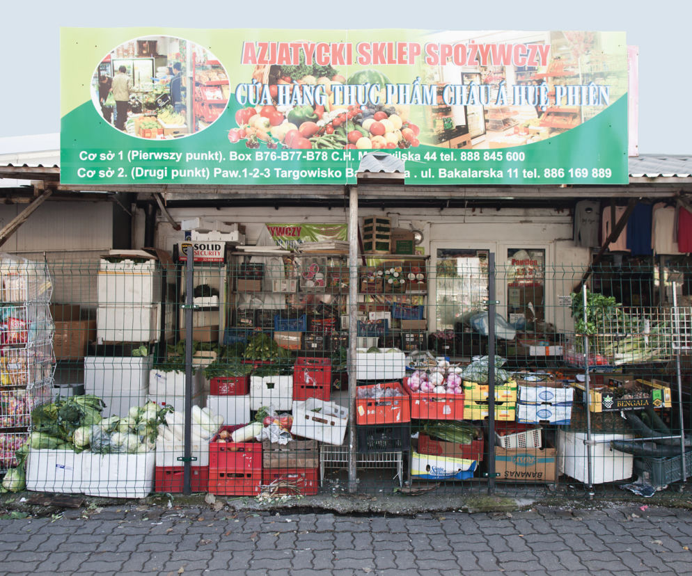 Front sklepu spożywczego z azjatyckimi produktami i warzywami wystawionymi przed wejściem na ryneczku. Na szyldzie widać adresy dwóch punktów oraz numer telefonu. To przykład lokalnego handlu przygranicznego, o którym przeczytasz na Super Biznes.