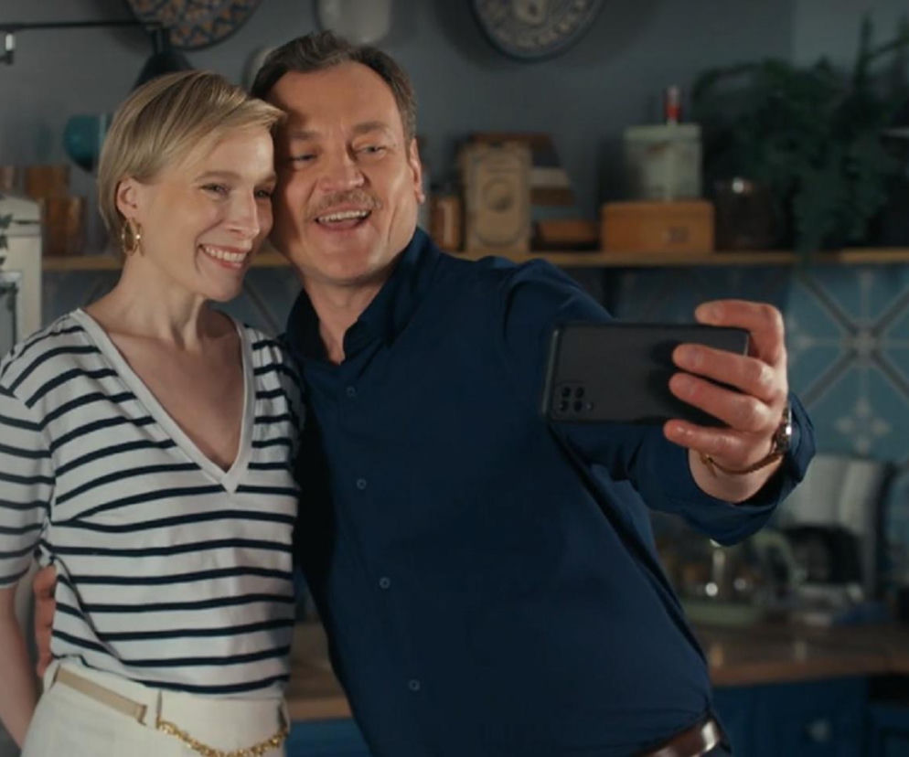 Uśmiechnięci Sonia (Weronika Nockowska) i Stefaniak (Paweł Ławrynowicz) w kuchni, robiący sobie selfie telefonem. Sonia w bluzce w paski, Robert w granatowej koszuli. Scena z odcinka Barw szczęścia, gdzie Sonia wybacza Stefaniakowi, o czym przeczytasz na Super Seriale.
