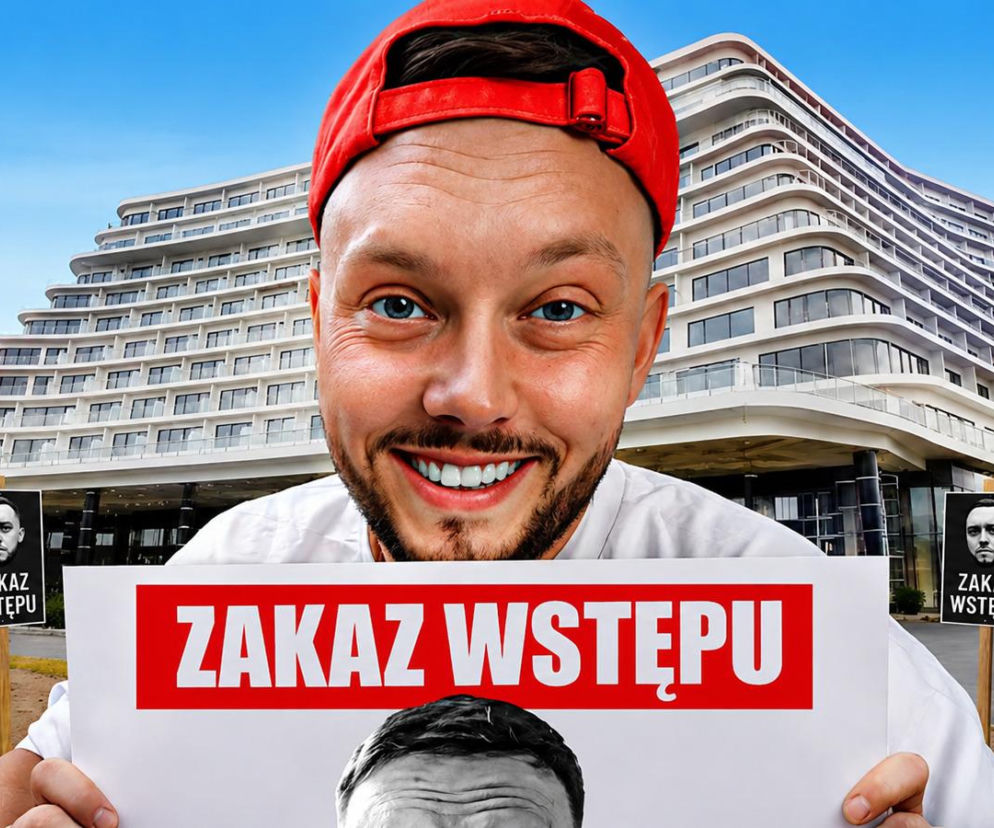 Uśmiechnięty Książulo trzyma tabliczkę z napisem Zakaz Wstępu na tle hotelu Gołębiewski. Więcej przeczytasz na SE Szczecin.