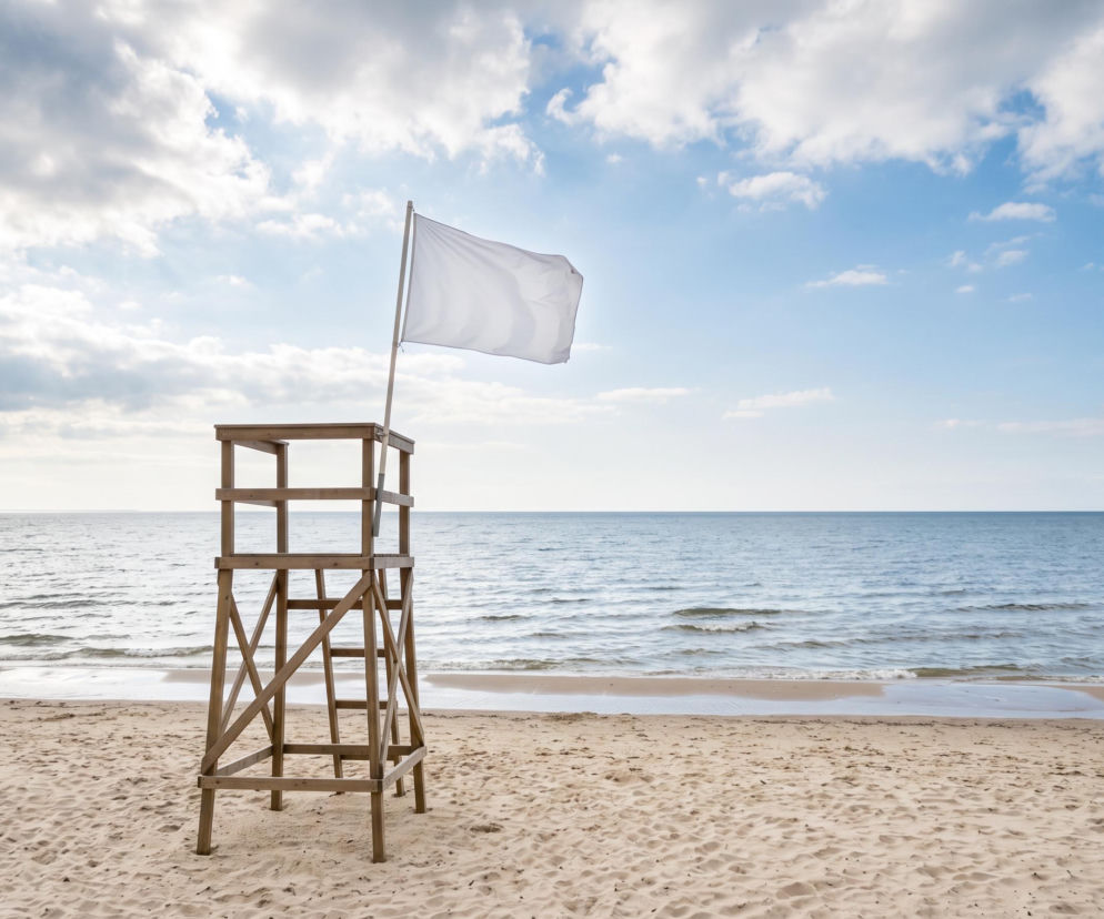 Drewniana wieża ratownicza z białą flagą na plaży w Grzybowie. O pogodzie nad morzem przeczytasz na SE Szczecin.