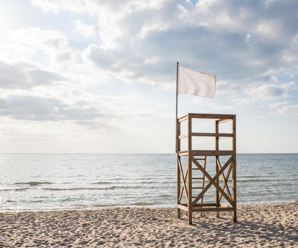 Drewniana wieża ratownika z białą flagą na plaży w Mechelinkach. O pogodzie nad morzem przeczytasz w Eska Trójmiasto.