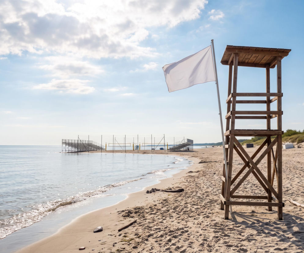 Biała flaga i wieża ratownicza na plaży w Ustce. O braku sinic i pogodzie przeczytasz na Eska Trójmiasto.