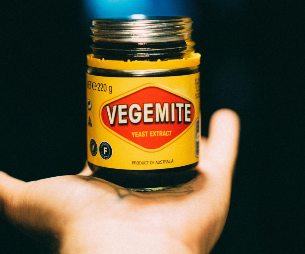 Otwarty słoik pasty Vegemite na dłoni wytatuowanej osoby. O zakazie tego produktu w więzieniach przeczytasz w Eskce.