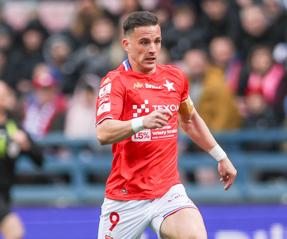 Napastnik Wisły Kraków Angel Rodado biegnie po boisku w czerwonej koszulce. O formie piłkarza przeczytasz na SE Supersport.