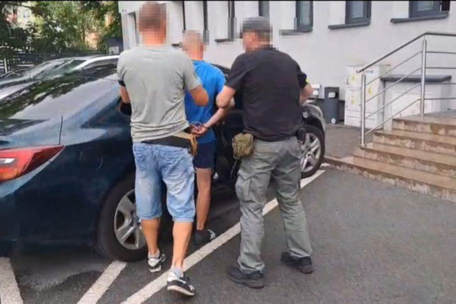 Policjanci doprowadzają skutego mężczyznę do radiowozu. O zarzutach dla 48-latka przeczytasz na Eska Lublin.