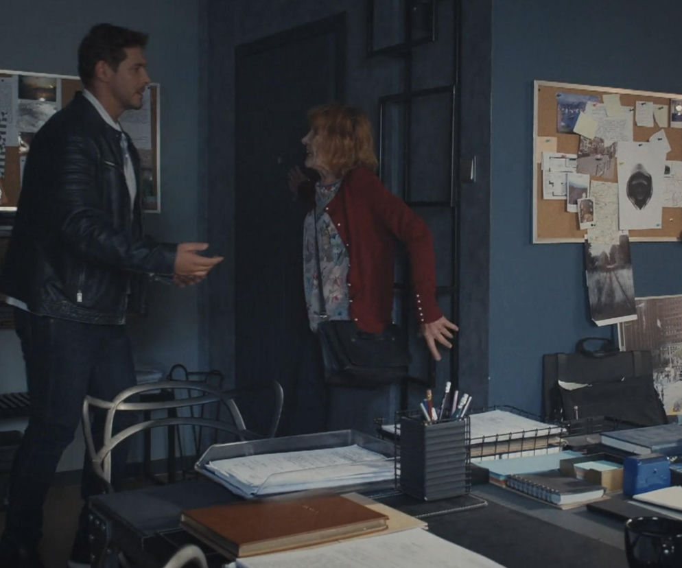 Marcin Chodakowski (Mikołaj Roznerski) rozmawia z panią Olą (Ewa Kolasińska) w biurze detektywistycznym, a za nimi widać tablice korkowe z przypiętymi dokumentami. Scena z serialu M jak miłość, o którym więcej przeczytasz na portalu Super Seriale.