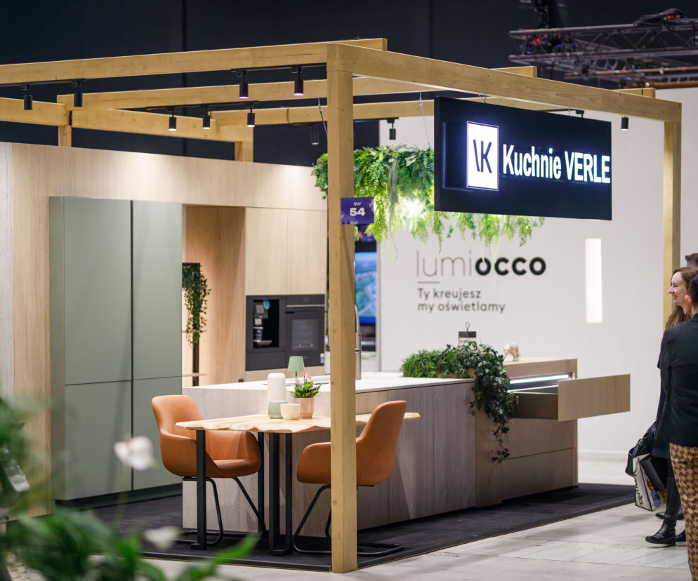Nowoczesne stoisko Kuchnie Verle z drewnianą konstrukcją i roślinnością na tle jasnej zabudowy kuchennej, z widocznymi logo firm i gośćmi branżowymi podczas 4 Design Days. O architekturze i designie można przeczytać na Architektura Murator Plus.